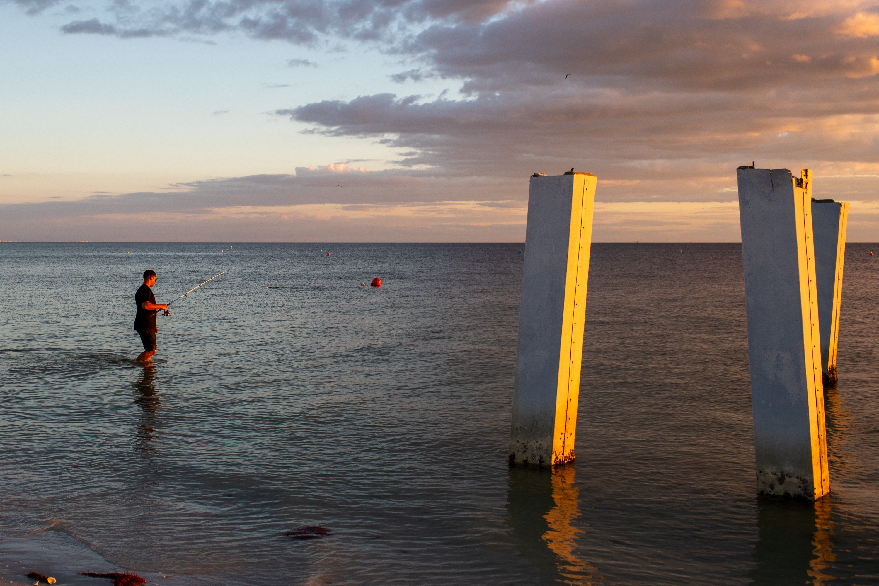 A person fishes next to a broken pier in Fort Myers Beach, Fla., in October. The city is still rebuilding after Hurricane Ian devastated the area in 2022. High costs for construction and insurance have made Fort Myers Beach unaffordable for many who called it home before.